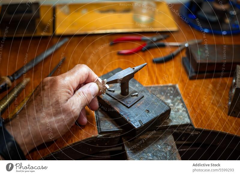 Goldschmied beim Herstellen und Reparieren von Goldschmuck in seiner Werkstatt mit einem Amboss. Juwelier bei der Arbeit an einem Silberschmuckstück. Klette