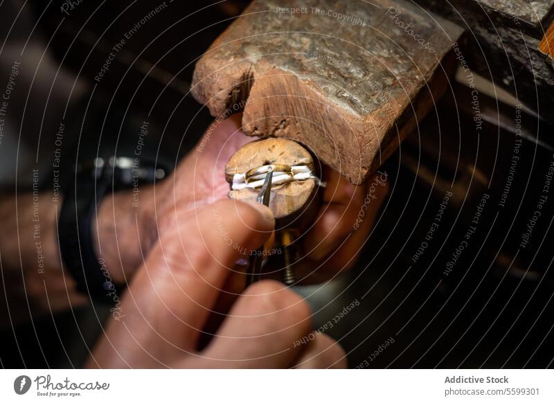 Ein Juwelier fasst einen Diamanten mit einem Stichel in einen Ring in einer Schmuckwerkstatt. Goldschmied bei der Herstellung eines Goldschmuckstücks.