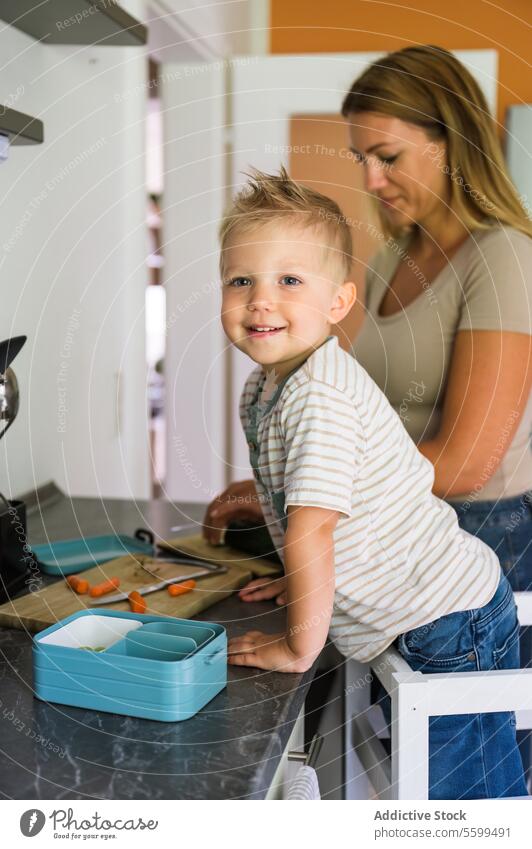 Fokussierte glückliche Mutter und lächelndes Kind Junge stehen in der Nähe von Küche Plattform zu Hause Sohn Lächeln vorbereiten Mittagessen Lunch-Box Podest