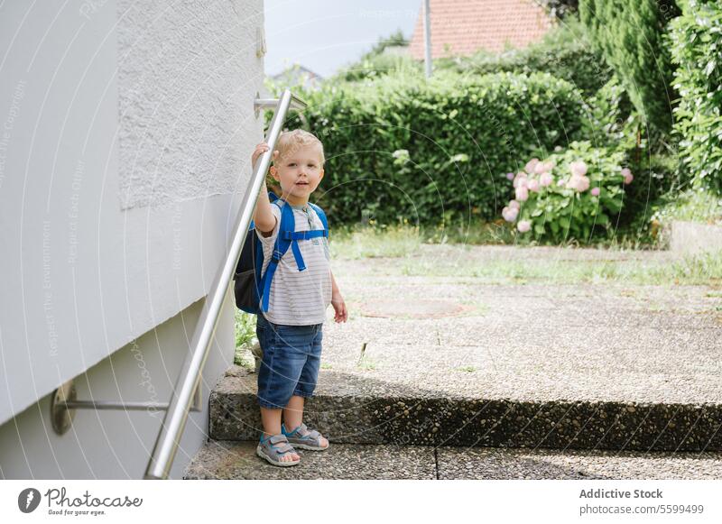 Glückliches Kind mit Rucksack im Freien stehend Junge Sommer Treppenhaus lässig Lächeln heiter niedlich bezaubernd Sonne Kindheit positiv tagsüber Lifestyle