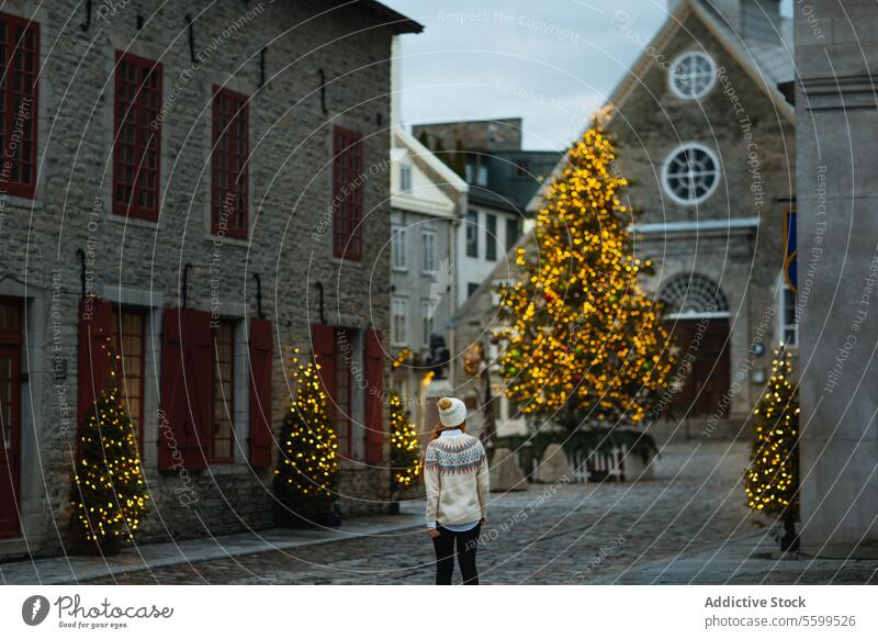Frau genießt die Weihnachtsbeleuchtung im historischen Viertel in Quebec, Kanada Feiertag Lichter Weihnachtsbaum Rückansicht Revier Kopfsteinpflaster Straße
