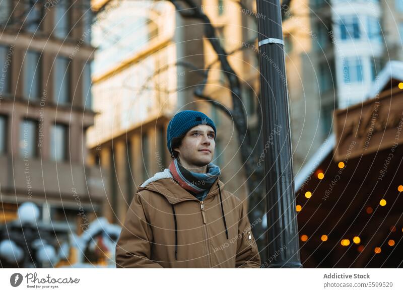 Junger Mann, der in einer winterlichen Stadt in Quebec, Kanada, nachdenkt jung Erwachsener männlich betrachtend urban Winter Einstellung lässig Outfit Straße