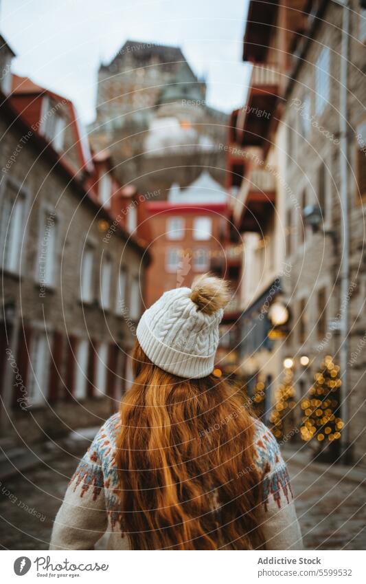 Frau im Winterspaziergang durch die historische Gasse der Stadt Quebec rote Haare Beanie Kopfsteinpflaster Straße festlich Weihnachtsmarkt Lichter Großstadt alt