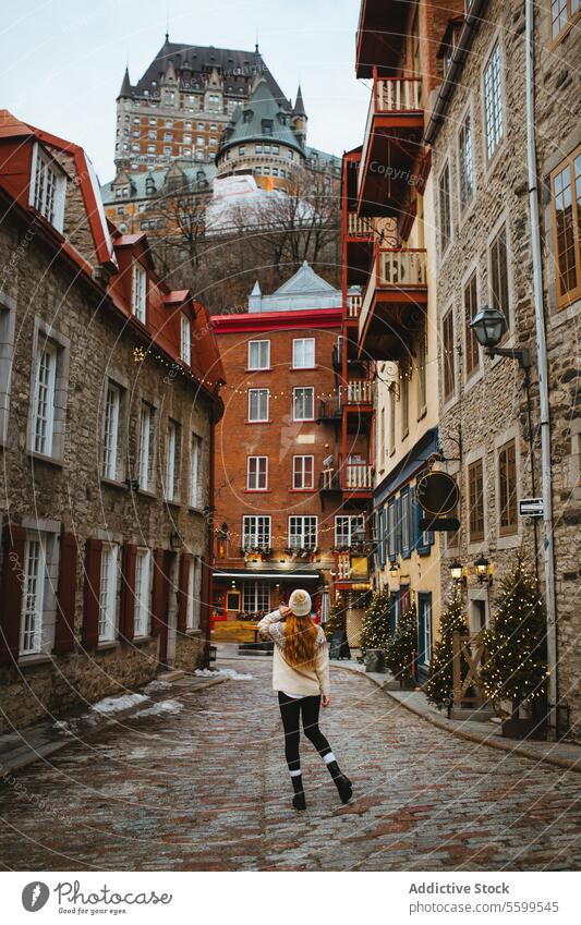 Charmante Altstadtstraße mit einem flanierenden Touristen in Quebec, Kanada Frau laufen Kopfsteinpflaster Straße historisch Ganzkörper festlich Lichter Schnee