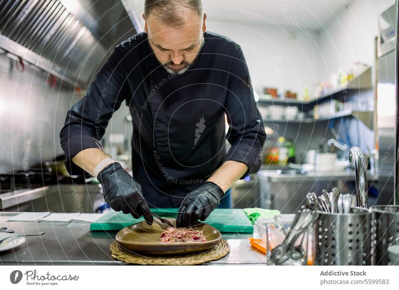 Männliche Person serviert Fleisch auf einem Teller in einer Restaurantküche Küchenchef Mann dienen Koch geschnitten Vanillerostbraten vorbereiten männlich