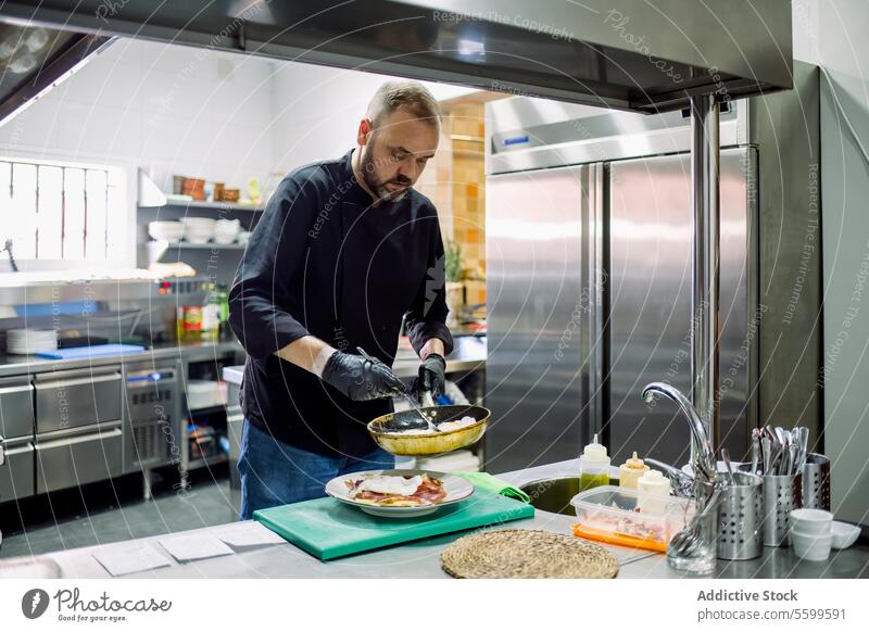 Männlicher Koch serviert gebratenes Essen in der Küche Mann Küchenchef Bratpfanne kulinarisch Restaurant Lebensmittel vorbereiten Arbeit Pfanne Gas Speise