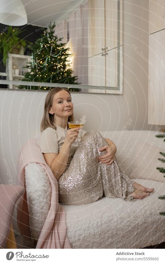 Junge Frau genießt einen Cocktail auf einer gemütlichen Couch zu Hause Liege heimwärts trinken Erholung Komfort Sitzen im Innenbereich lässig Lifestyle Freizeit