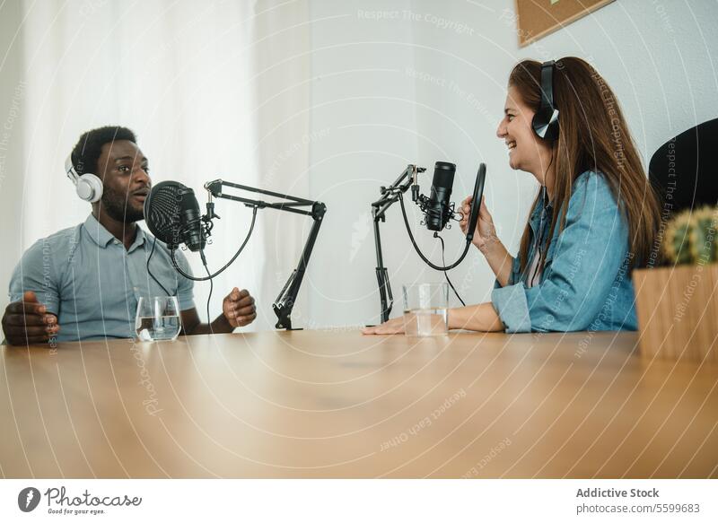 Multiethnische Kollegen nehmen gemeinsam einen Podcast auf Aufzeichnen Mitarbeiterin Kopfhörer Mikrofon reden sprechen Zusammensein Ausstrahlung multiethnisch