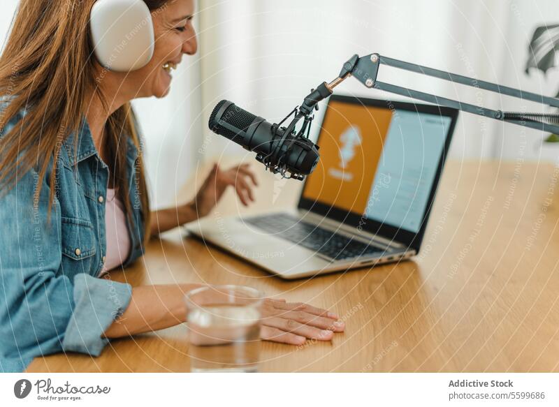 Frau mit Kopfhörern bei der Aufnahme eines Podcasts Aufzeichnen Ausstrahlung Browsen Laptop Lächeln Radio Wirt Mikrofon reden sprechen Klang Atelier Inhalt