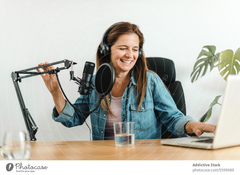 Frau benutzt Laptop und nimmt Podcast auf Aufzeichnen Browsen benutzend Mikrofon Atelier Kopfhörer Radio Gerät Audio Ausstrahlung sitzen Tisch Tippen Surfen