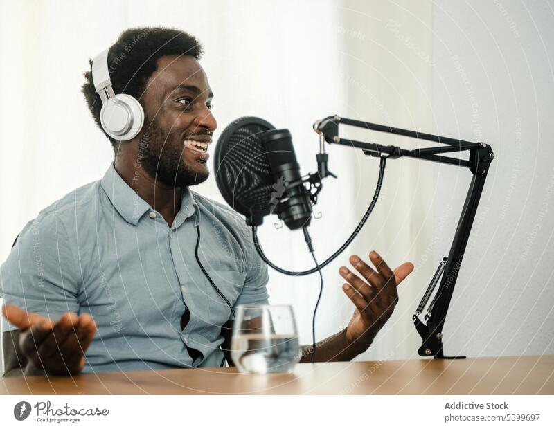 Schwarzer Mann nimmt Podcast auf und gestikuliert Aufzeichnen Mikrofon sprechen reden gestikulieren Radio Wirt männlich ethnisch schwarz Afroamerikaner