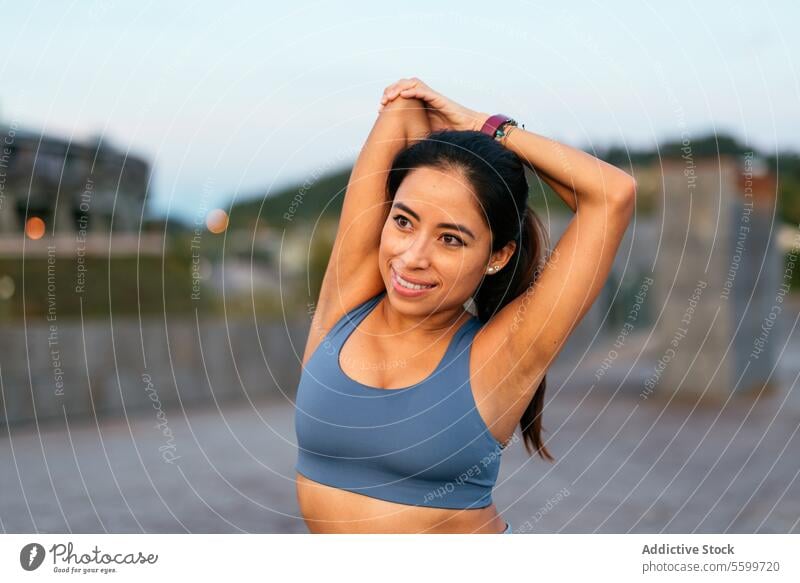 Lächelnde Frau beim Dehnen im Freien nach dem Sport Lateinamerikaner strecken Training Übung Fitness Gesundheit Wohlbefinden Sportbekleidung Sportkleidung