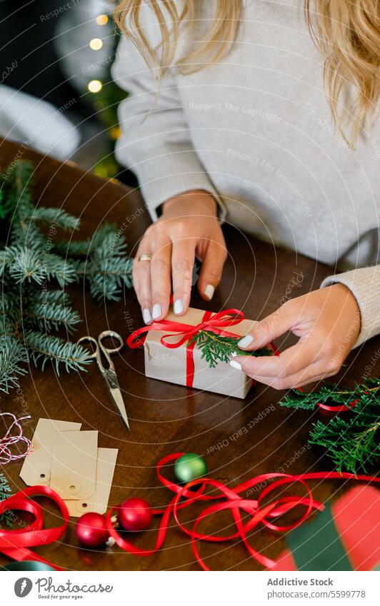 Frau macht schönes Weihnachtsgeschenk am Tisch Weihnachten Person Feier präsentieren Verpackung Feiertag Hand Kasten Überraschung rot festlich Bändchen
