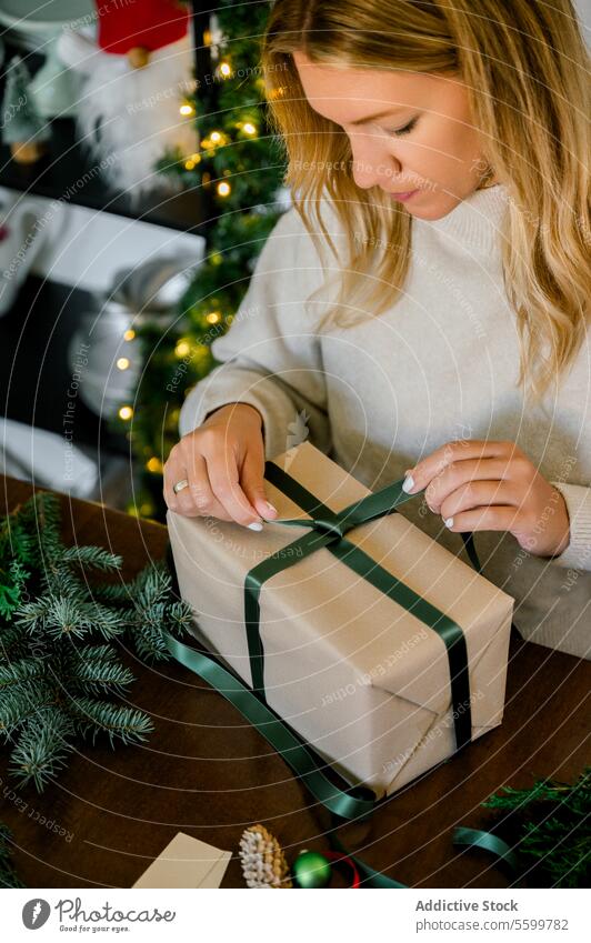 Frau packt Weihnachtsgeschenk zu Hause ein Bändchen professionell Person Objekte Veranstaltung Papier dekorierend im Innenbereich Überraschung Verpackung