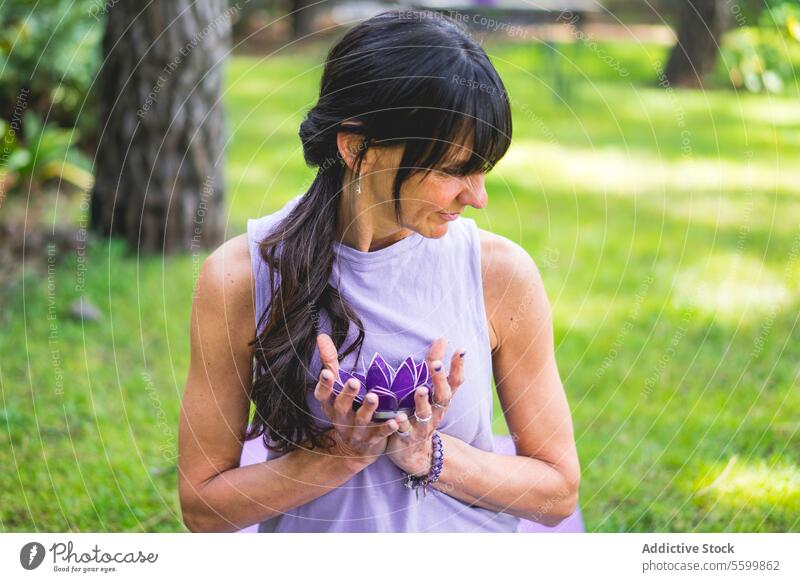 Mid erwachsene Frau hält hält ein lila Glas Lotus. Yoga und Meditation Konzept. aquatisch Hinterhof Gleichgewicht schön Schönheit Windstille Ruhe