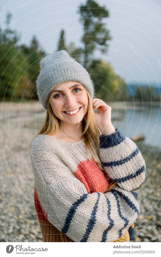 Lächelnde Frau in warmer Kleidung gestrickt Pullover Glück heiter See Natur Landschaft Hut Ufer Freude Saison Stil Wochenende positiv ruhen sich[Akk] entspannen