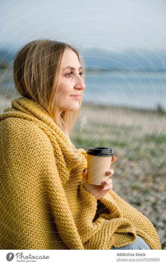 Junge blonde Frau in Decke eingewickelt mit Kaffeetasse am Seeufer Person Natur im Freien Urlaub Sitzen Wasser Erwachsener Lifestyle Erholung eine Person