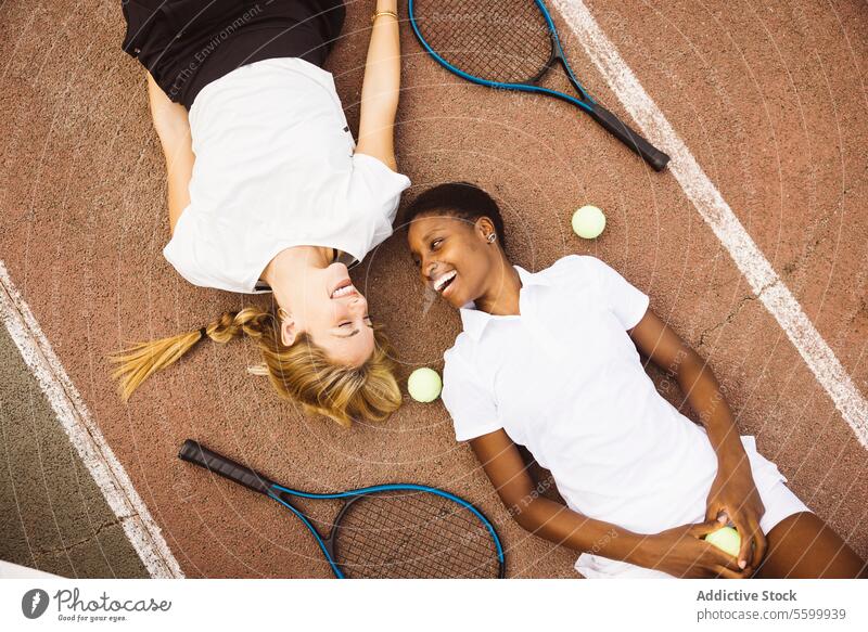 Porträt von zwei Frauen, die auf einem Tennisplatz liegen. aktiver Lebensstil Aktivität Amateur Athlet Ball schön schöne Frauen heiter Konkurrenz Gericht