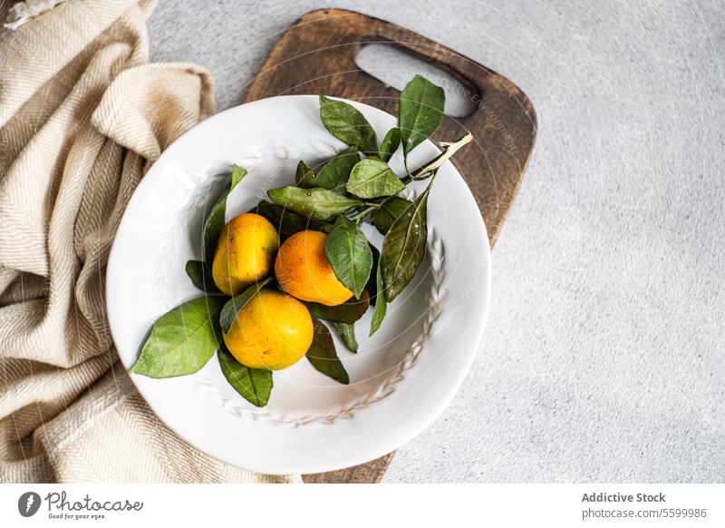 Rustikaler Charme mit Zitrus-Akzenten rustikal Mandarine Zitrusfrüchte weiße Platte texturiert beige Serviette Einfachheit frisch Frucht organisch Geschirr