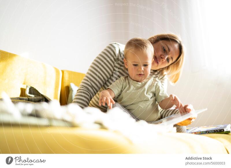 Mutter und Kleinkind genießen ein Buch auf dem Sofa lesen heimwärts Bilderbuch Kind Engagement fürsorglich bequem Liege Familie Bonden Lernen Bildung Brutpflege