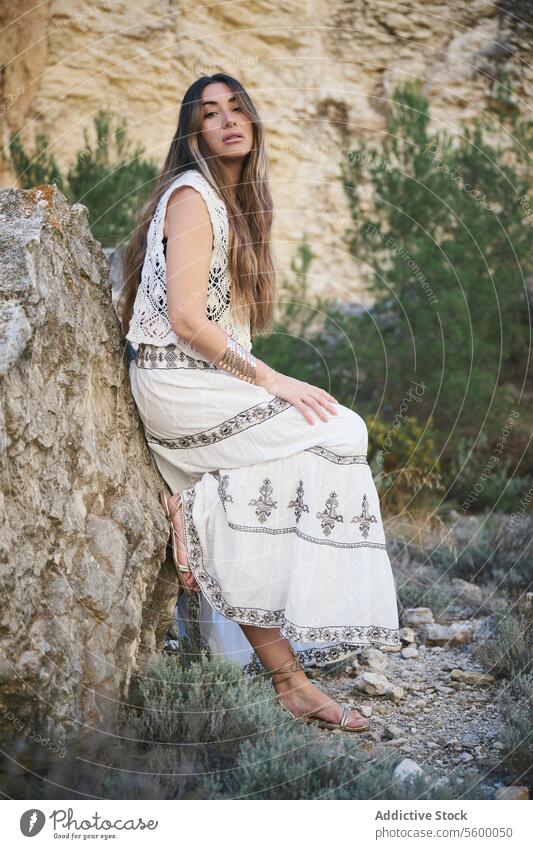 Frau in einem bestickten Kleid neben einem Felsen weiß Bohemien Landschaft natürlich im Freien Gelassenheit Behaarung fließen fettarm Sommer Stil Mode Eleganz