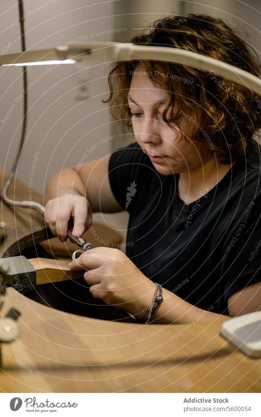 Konzentrierte erwachsene Kunsthandwerkerin, die in einem Schmuckatelier arbeitet arbeiten Beruf Herstellung Kompetenz Schreibtisch Kreativität Fotografie