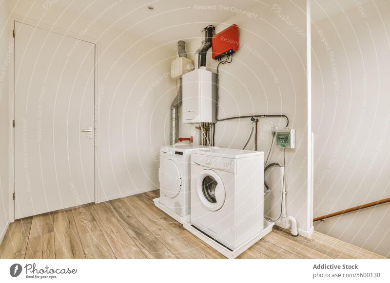 Weiße Waschküche mit Waschmaschine Wäscherei Trockner Vorrichtung Tür Wand weiß elektronisch Röhren Draht Heizkörper Raum heimisch Arbeit Haushalt modern