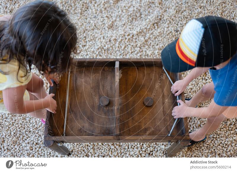 Zwei Kinder arbeiten gemeinsam an einer Holzschublade Teamwork hölzern Schublade Fixierung Problemlösung Zusammenarbeit Ansicht von oben jung Möbel Reparatur