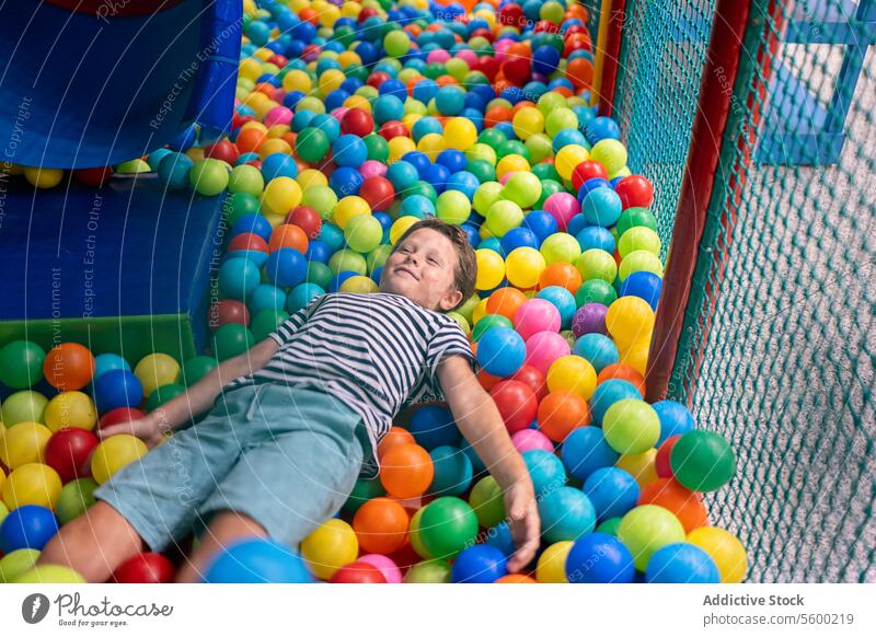 Kleiner Junge, der sich auf einem Indoor-Spielplatz an einem bunten Ballspielplatz vergnügt Kind spielen farbenfroh im Innenbereich Freude Spaß Freizeit