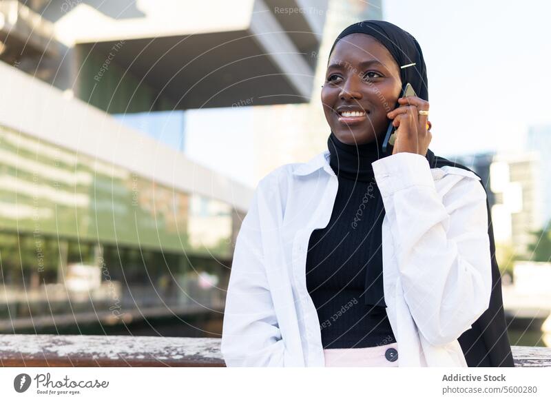 Glückliche Frau im Hidschab, die in der Stadt über ein Mobiltelefon spricht Geschäftsfrau Hijab reden Smartphone Augen geschlossen heiter Mobile Telefon modern