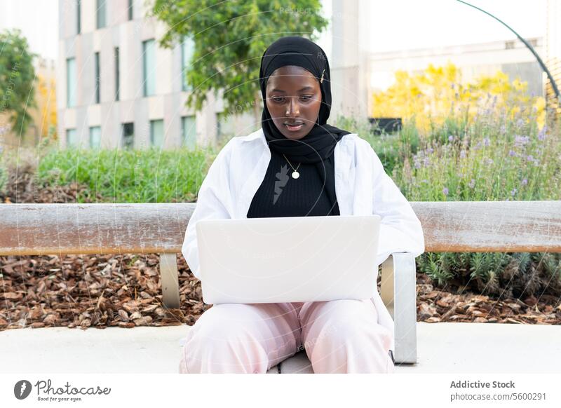 Freiberuflerin im Hidschab arbeitet am Laptop in der Stadt Geschäftsfrau Hijab muslimisch ernst Konzentration Tradition Kopftuch Computer Internet Sitzen Bank