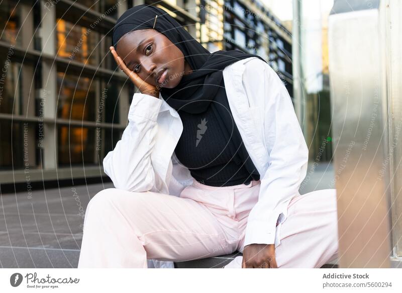Seriöse Geschäftsfrau im Hijab in der Stadt sitzend schwarz emotionslos ernst formal berührend Gesicht Unternehmer professionell Beruf Manager Großstadt