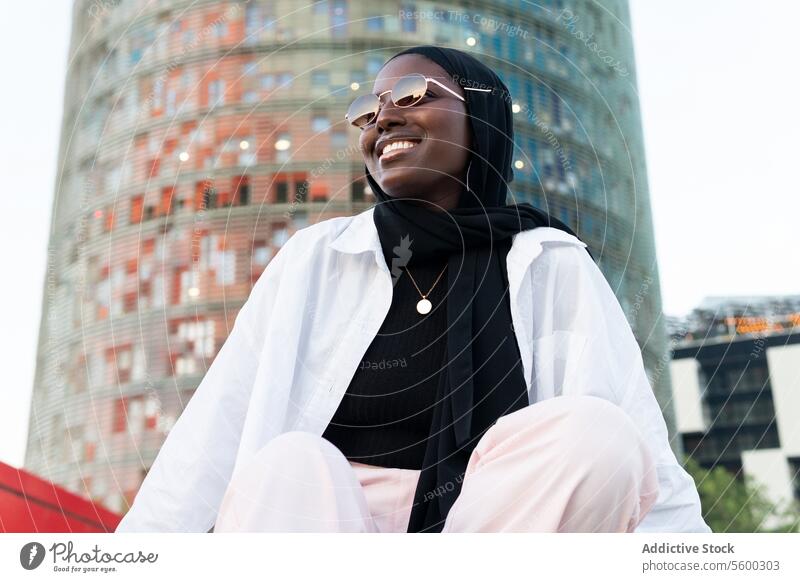 Stilvolle Geschäftsfrau mit Hijab und Sonnenbrille in der Stadt schwarz Unternehmer modisch Gebäude von unten stylisch Großstadt Unschärfe professionell Beruf