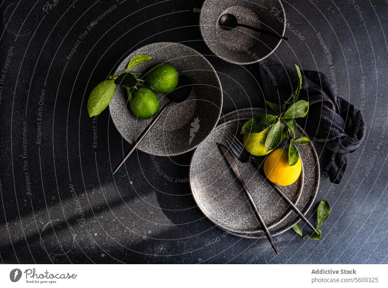 Elegantes Keramikgeschirr mit grünen Zitronen auf dunklem Hintergrund Geschirr dunkel Ordnung künstlerisch frisch Speise Frucht Küchengeräte elegant Design