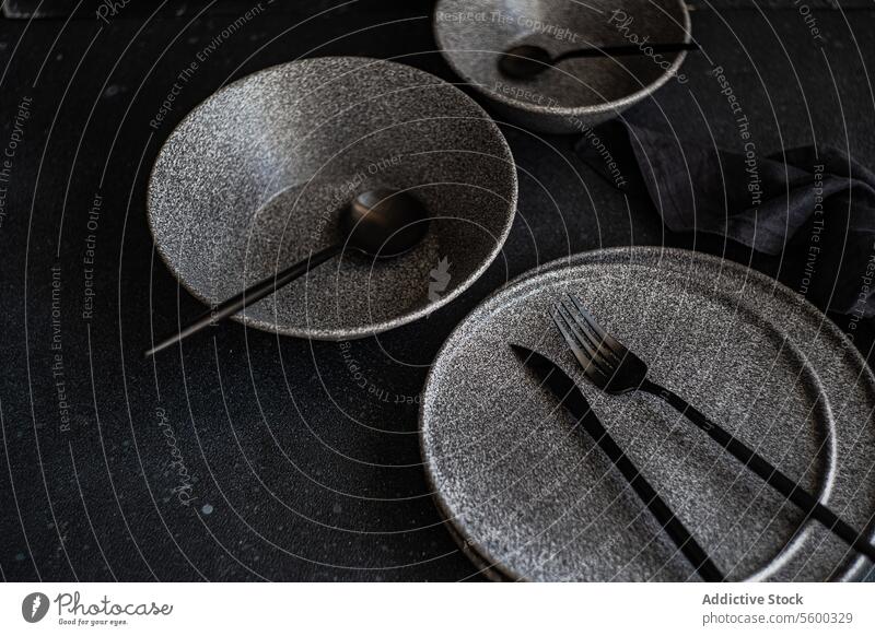Modernes dunkles Geschirr auf schwarzem Hintergrund dunkel Steingut Gerichte Utensilien elegant Besteck Ordnung speisend Einstellung anspruchsvoll Teller