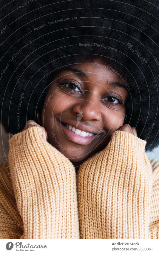 Schwarze Frau, die ihre Hände auf ihr Gesicht stützt und in die Kamera schaut Lächeln Porträt heiter Afro-Look Vorschein lustig schwarz Afroamerikaner