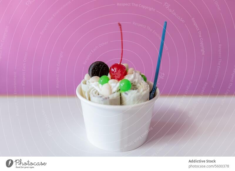 Nahaufnahme eines gerollten Eises, dekoriert mit einer Kirsche, einem Keks und grünem Blasenbelag Speiseeis Belag dekorieren Löffel Schaumblase Molekül Kübel