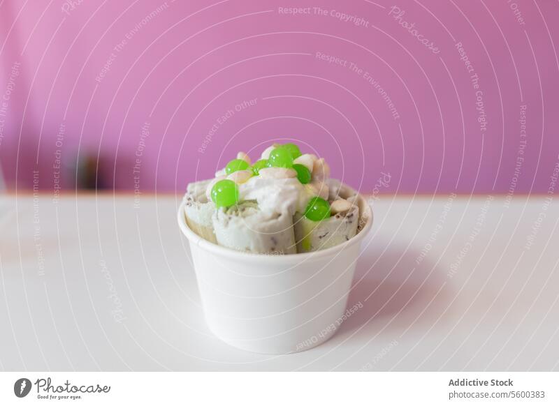 Nahaufnahme eines gerollten Eises, dekoriert mit grünen Blasen und Joghurt-Toppings Speiseeis Belag dekorieren Löffel Schaumblase Molekül Kübel melken Sahne