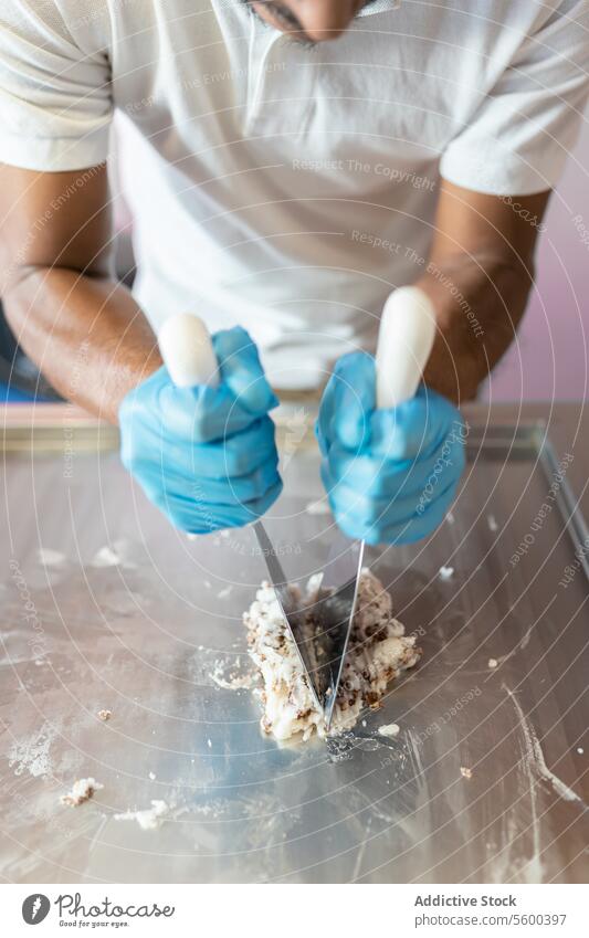 Ein Arbeiter benutzt Spatel, um eine Rolle in einer Eiscrememaschine vorzubereiten Mann Erwachsener reif hispanisch Latein weiß Hemd Spachtel hacken Schokolade