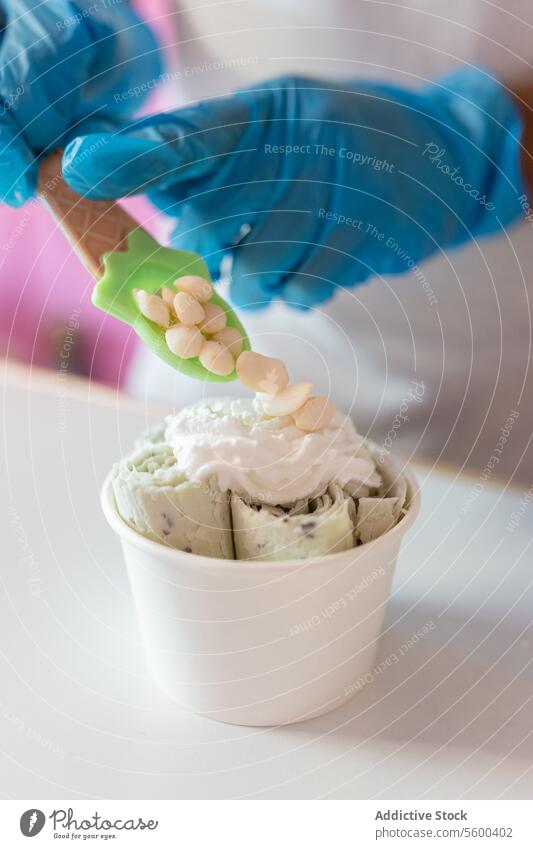 Ein Arbeiter dekoriert mit einem Löffel einen gerollten Eisbecher mit Joghurt-Bubble-Toppings Mann Erwachsener Speiseeis Belag dekorieren Schaumblase Molekül
