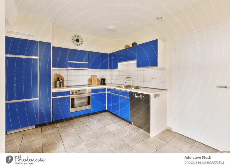 Blaue Küche mit Schränken und modernen Geräten blau Kabinett Utensil Uhr Einführung Mikrowelle Geschirrspüler Waschbecken Wasserhahn Innenbereich Vorrichtung