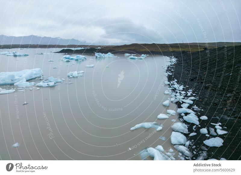 Gletschergewässer und vulkanisches Ufer Weitwinkel Ansicht Eisberg Wasser ruhig Asche glazial Landschaft Vatnajökull Nationalpark Island Windstille kalt