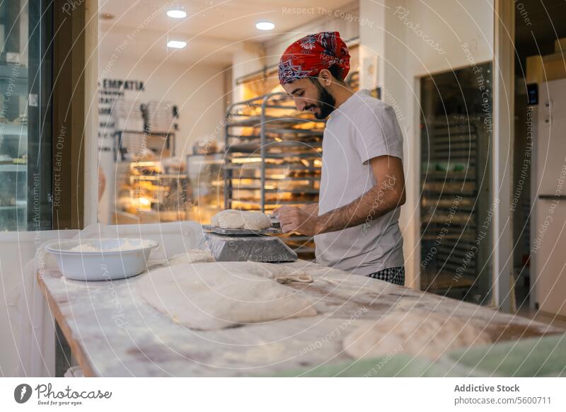 Arabischer Bäcker wiegt Teig mit Waage arabisch Teigwaren Schulterblatt Brot Skala Gewichtung Vorbereitung Bäckerei Herstellung Glück Lächeln Mehl roh Tisch