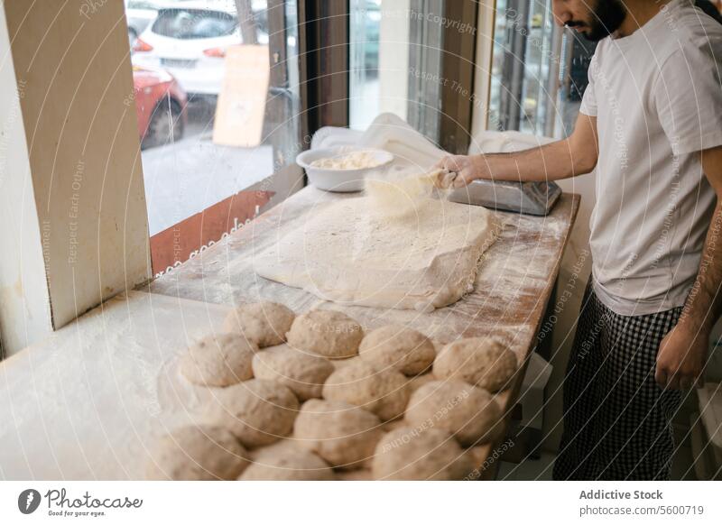Bäcker streut Mehl auf den Teig arabisch Teigwaren Bäckerei Vorbereitung Brot Fermentation Hefe frisch Ofen Senior Pizza Focaccia Küche Mann männlich Person