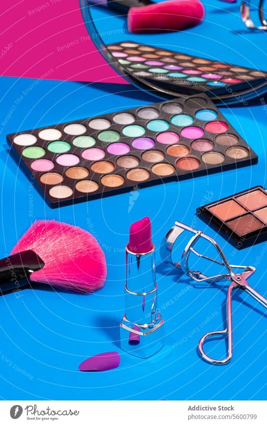 Schminkutensilien auf blauem und rosa Hintergrund Make-up Schönheit Lidschatten Palette Lippenstift Wimpernzange erröten Bürste Schwamm kompakt Pulver
