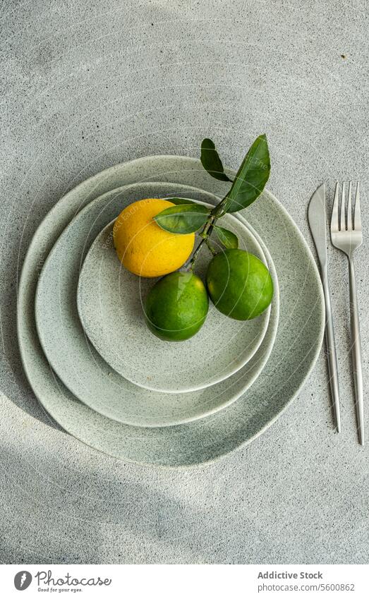 Zitrusfrüchte auf gestapelten Keramiktellern Früchte Platten modern Küche Ästhetik natürlich Urelemente Overhead Zitrone Kalk grün gelb Geschirr minimalistisch