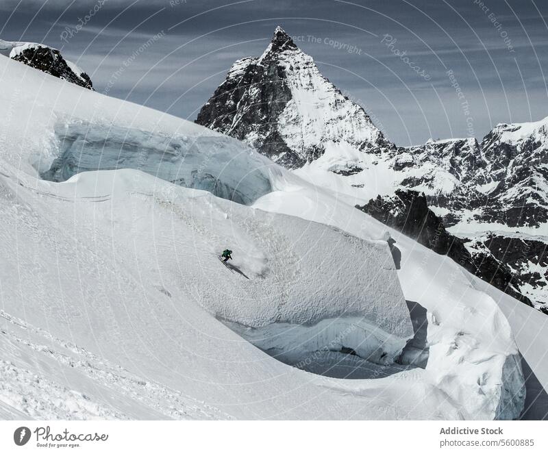 Von oben von anonymen Snowboarder Praxis von Berg in Winter Tag in den Schweizer Alpen Schnee Landschaft verschneite Berghang Felsen Berge u. Gebirge sonnig