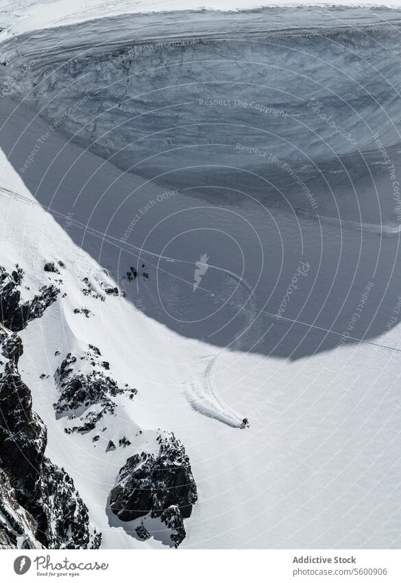 Von oben anonymer Snowboarder, der an einem Wintertag in den Schweizer Alpen vom Berg springt Schnee Landschaft verschneite Berghang Felsen Berge u. Gebirge