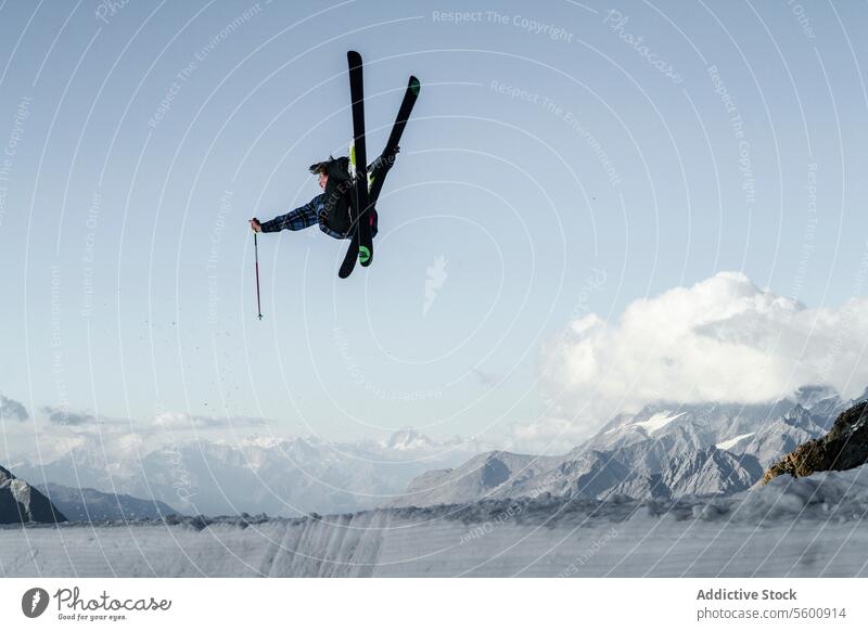 Anonymer sorgloser Mann beim Skifahren und Springen auf einem verschneiten Berg, während er einen Wintertag in den Schweizer Alpen genießt Skifahrer springen