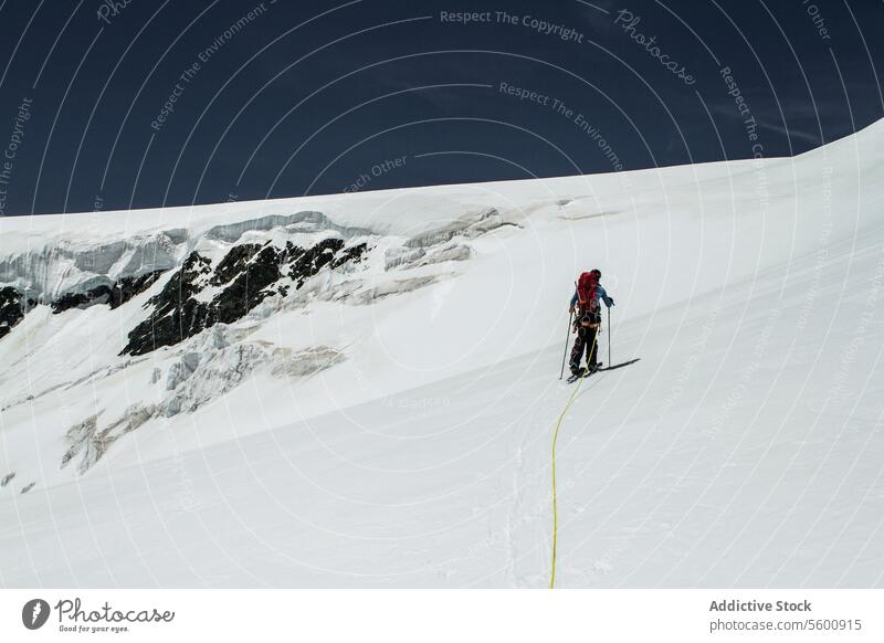 Rückenansicht eines anonymen Mannes beim Wandern auf einem schneebedeckten Berg vor blauem Himmel in den Schweizer Alpen an einem sonnigen Tag Backpacker Ski